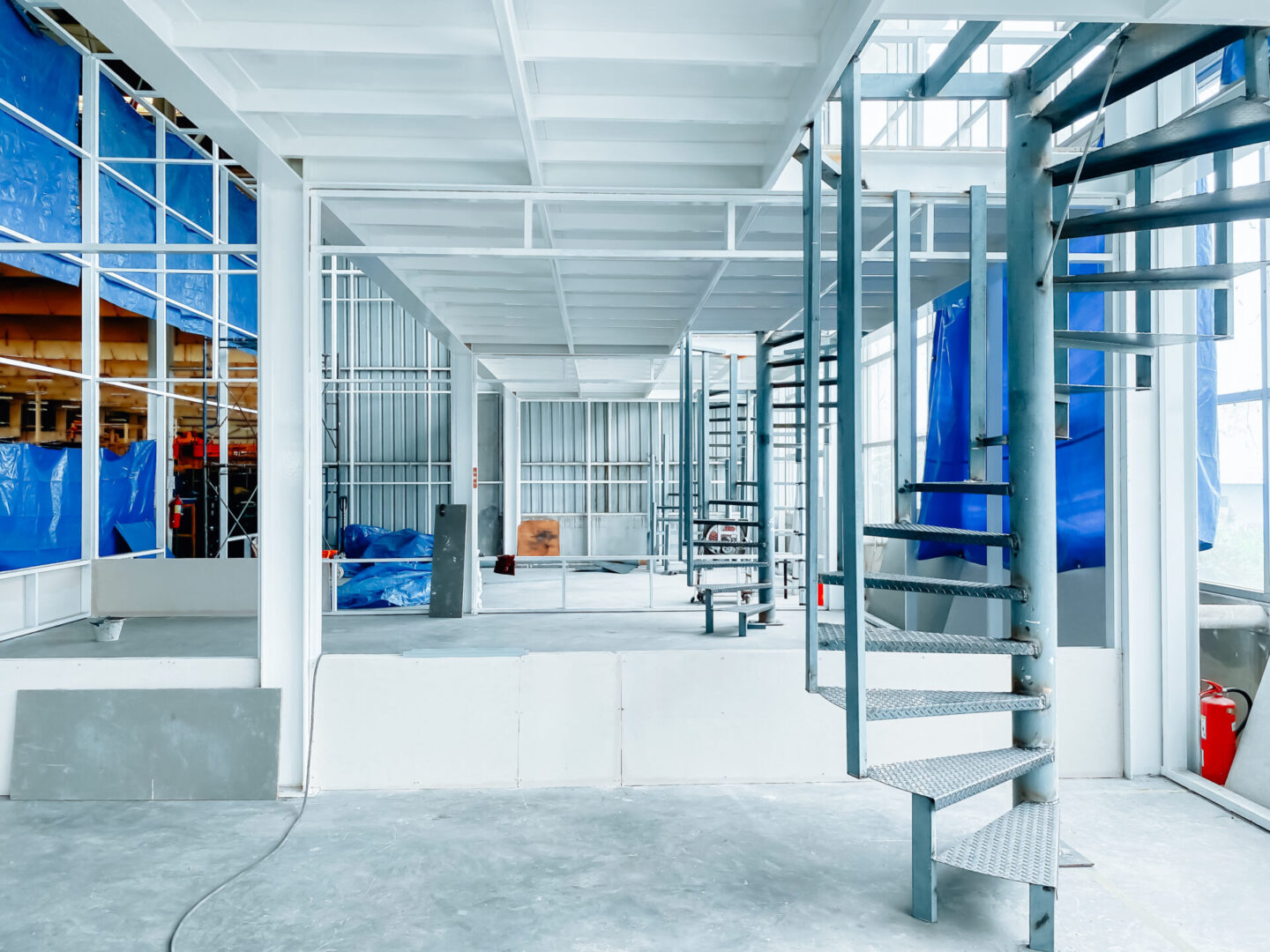 A bright, modern indoor space with metal spiral staircases and industrial design.