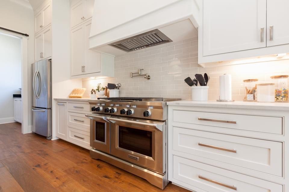 Modern kitchen with stainless steel stove and white cabinets.
