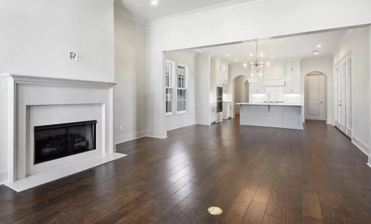 Spacious living area with dark hardwood floors and white walls.