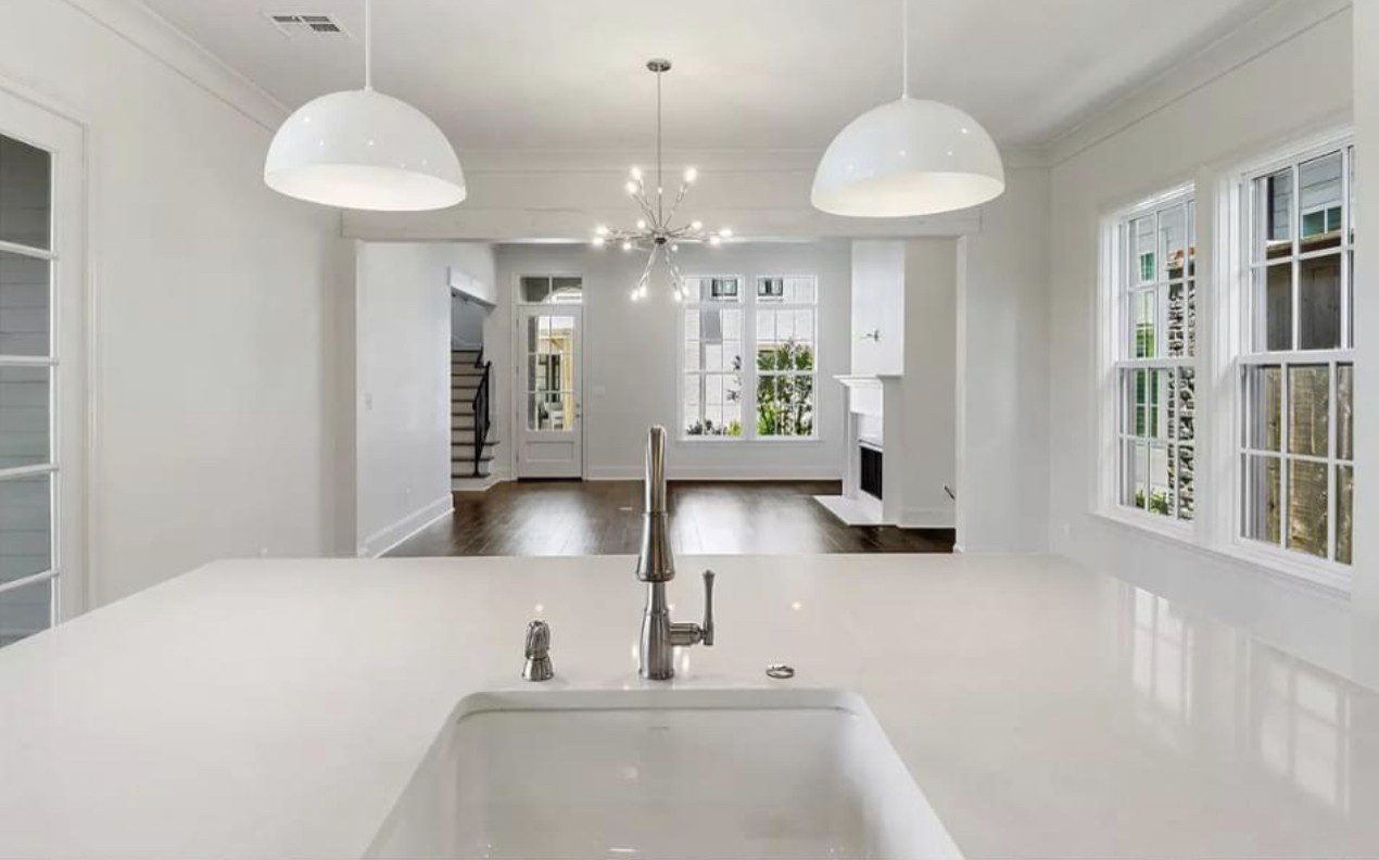 Modern kitchen with white countertops and pendant lights.